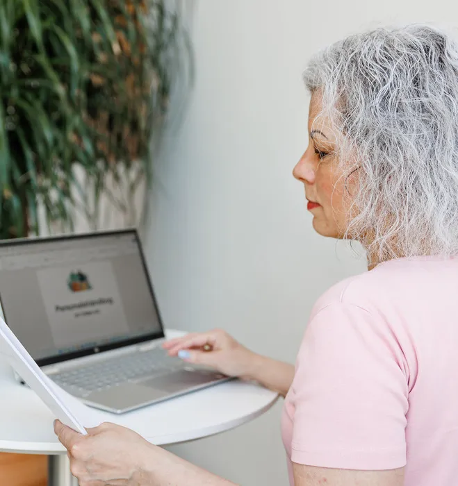 Kvinde i lyserød t-shirt arbejder ved computer