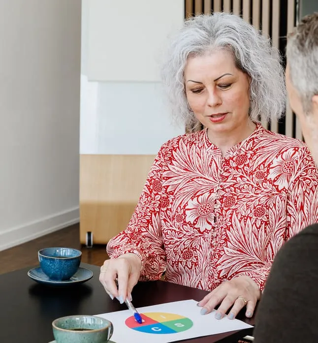 Kvinde med rød skjorte sidder ved bord og rådgiver
