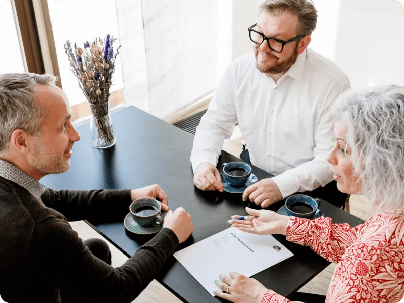 Kvinde i rød skjorte og 2 mænd holder møde