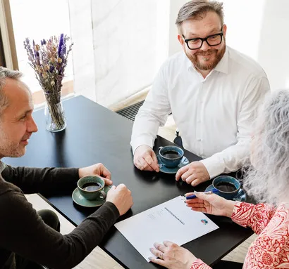3 mennesker holder møde omkring et bord