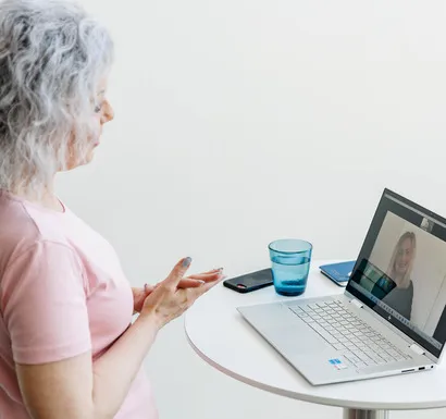 Kvinde i lyserød tshirt holder online video møde